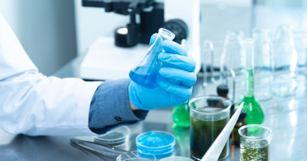 Gloved hand holding a beaker in a lab