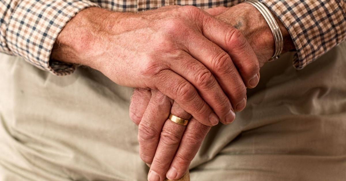 Hands of an elderly man on a cane