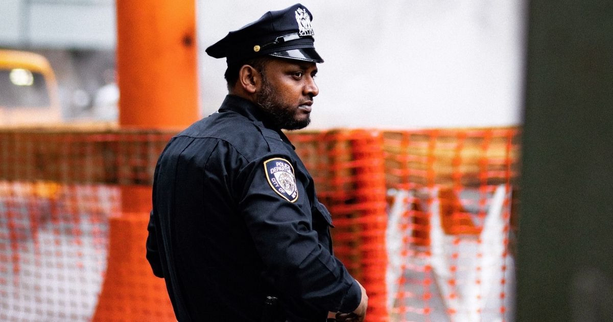NYC police officer standing in front of orange fencing