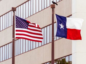 US and TX flags in front of building