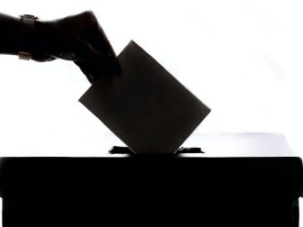 Silhouette of hand placing ballot in box