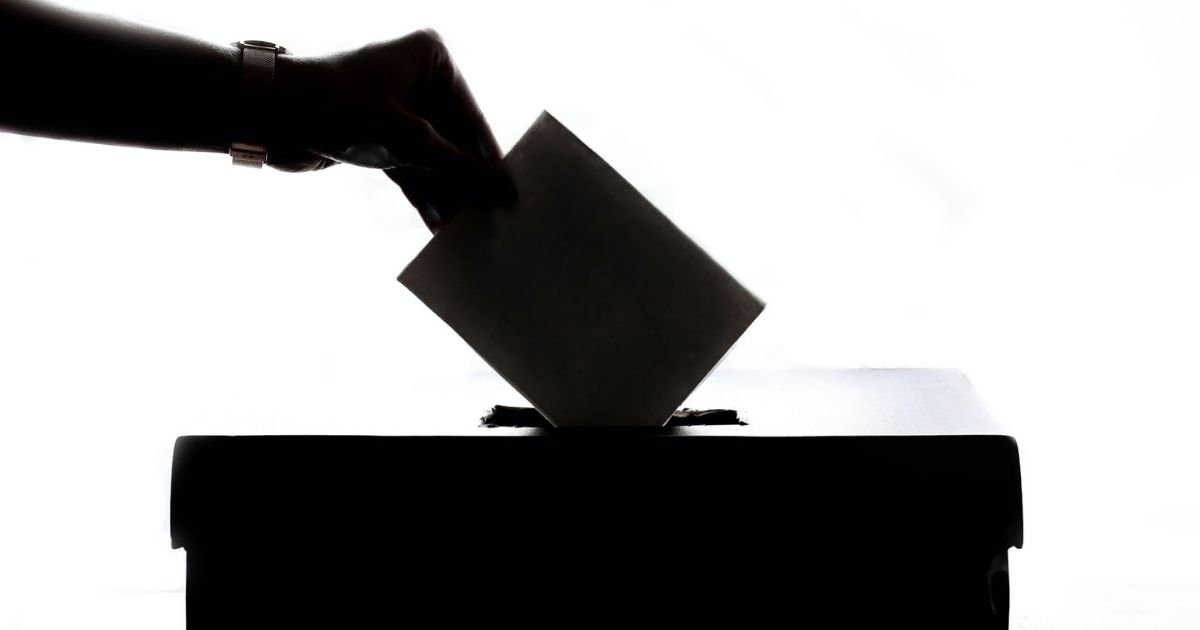 Silhouette of hand placing ballot in box