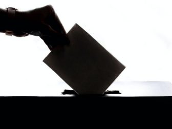 Hand putting ballot into a box