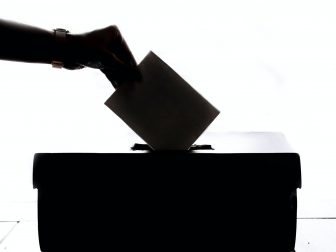 Shadow of hand dropping ballot in box