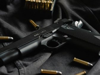 A black handgun on black cloth, with ammunition