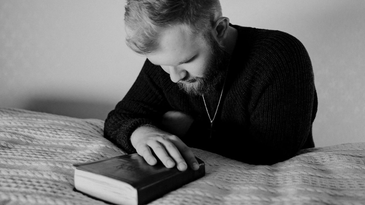 Grayscale Photo of a Bearded Man Praying