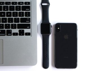 Macbook, Apple Watch, and iPhone lined up on a white surface