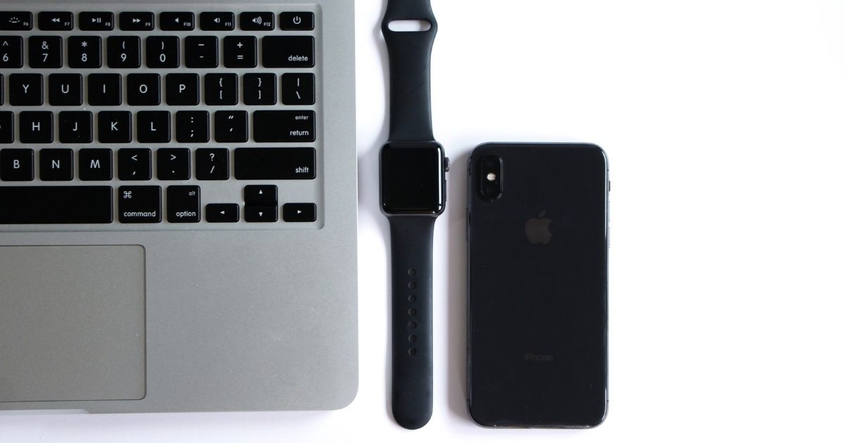 Macbook, Apple Watch, and iPhone lined up on a white surface