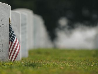 US flag on green grass next to headstone