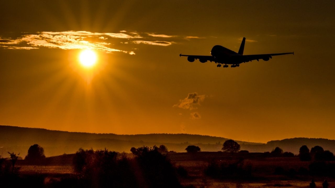 Silhouette of airplane flying over fields