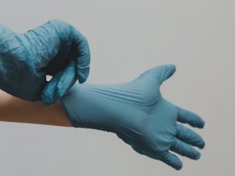 Hands putting on blue latex gloves