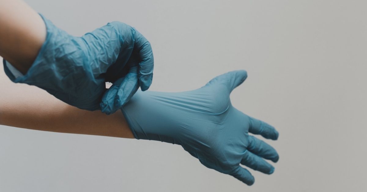 Hands putting on blue latex gloves