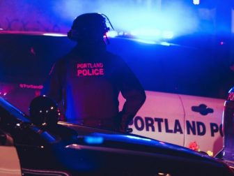 Police office taking in the scene during another night of Black Lives Matter protests in Portland, Oregon.