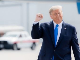 President Donald J. Trump gestures with a fist pump as he walks across the tarmac.