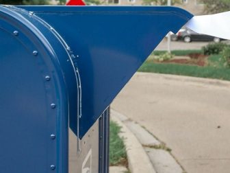 A person putting a letter in a mailbox.