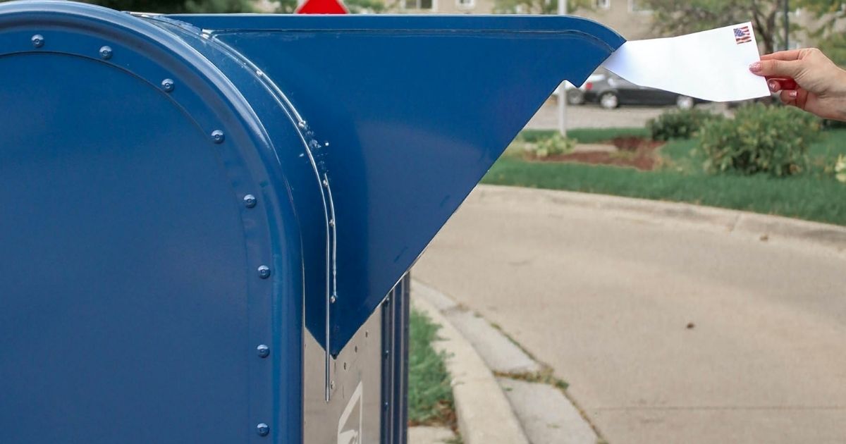 A person putting a letter in a mailbox.