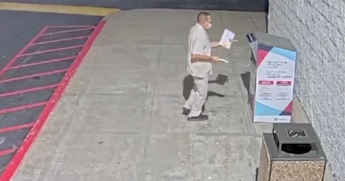 This screenshot from a surveillance camera covering a ballot box shows a man delivering multiple ballots to a drop box.