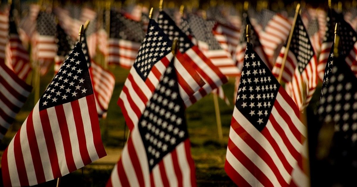 Several small American flags sit placed in the ground.