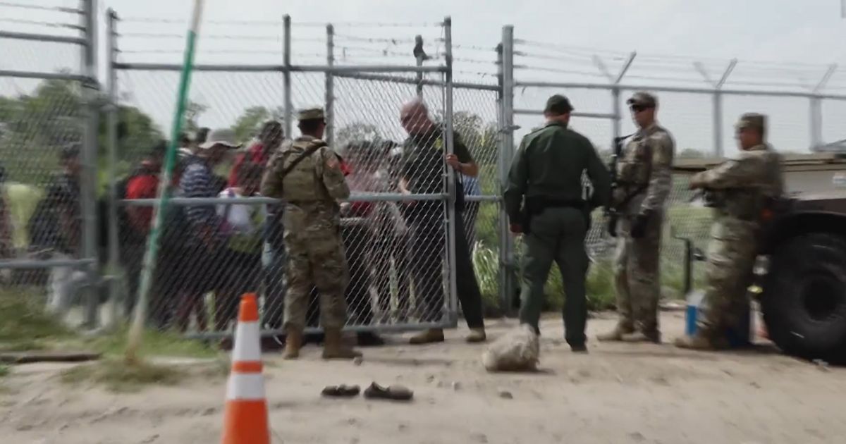 Border Patrol agents are opening a gate in this photo.