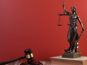 A statue of Lady Justice and a judge gavel are seen in this photo.
