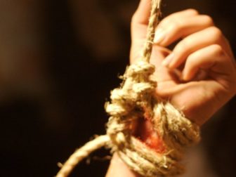 A hand bound by rope is seen in this photo.