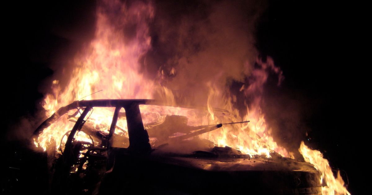 A burning car at night is seen in this photo.