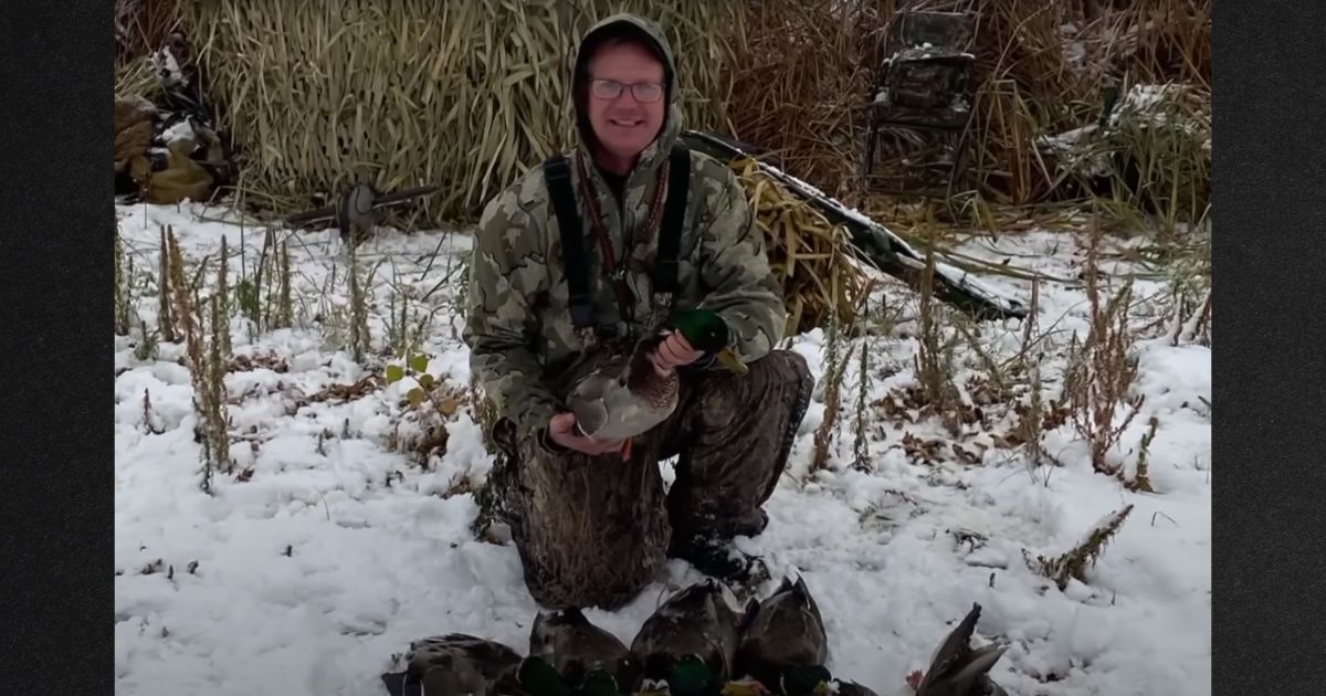 A hunter holds a duck in this photo.