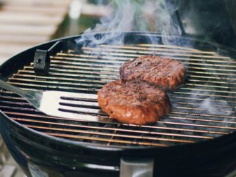 Photo of burgers cooking on a grill.