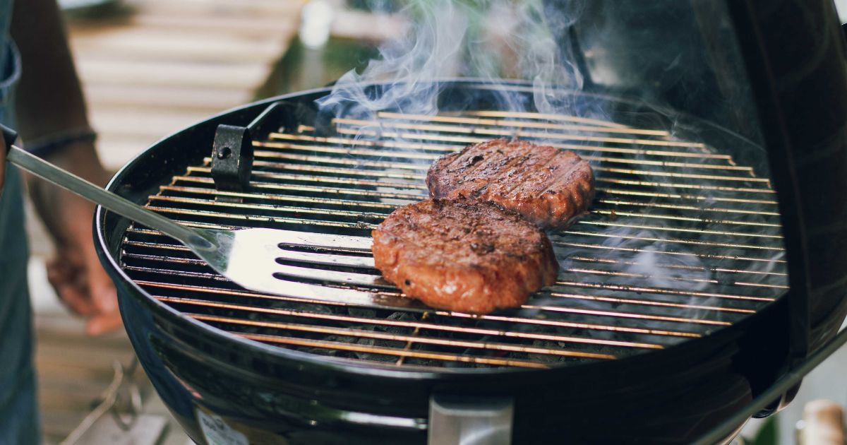 Photo of burgers cooking on a grill.