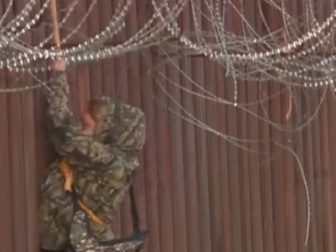 In a scene recorded by Fox News, an illegal alien uses a rope to scale down the side of a border fence in Arizona. (@BillFOXLA / Twitter screen shot)