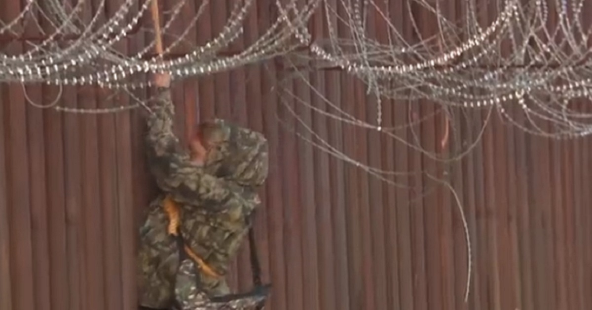 In a scene recorded by Fox News, an illegal alien uses a rope to scale down the side of a border fence in Arizona. (@BillFOXLA / Twitter screen shot)