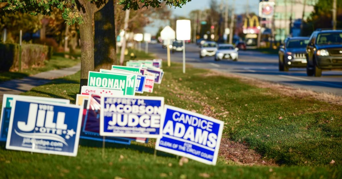 Motorists pass campaign signs just-outside the "No Electioneering" boundary in DuPage County, IL, outside Chicago.