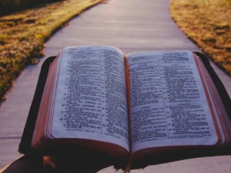 A person holding an open Bible.