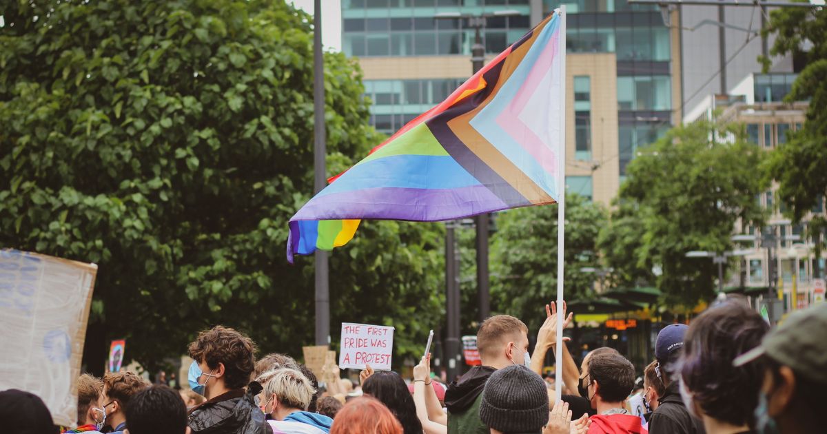 Protesters gathered in a street with a trans flag.