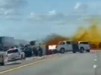 Crash-scene footage shows orange vapor rising over a highway packed with stopped vehicles.