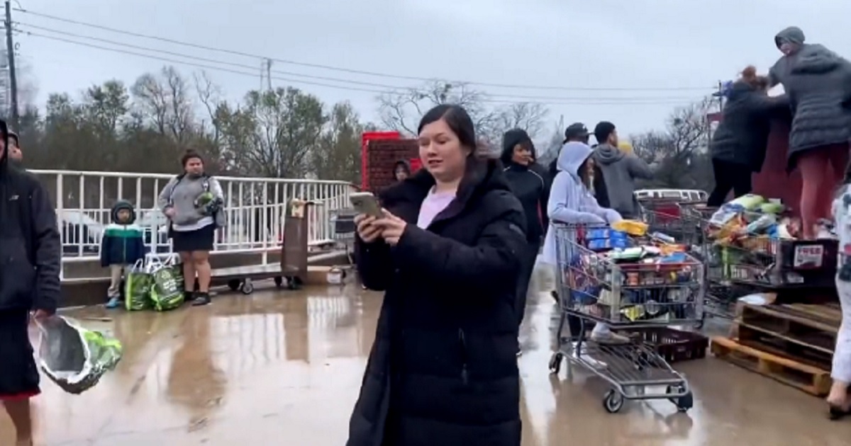 A woman uses her cell phone to record a mob of scavengers that descended on a dumpster outside a supermarket in Austin, Texas, on Thursday after the store discarded food potentially spoiled by a power outage.