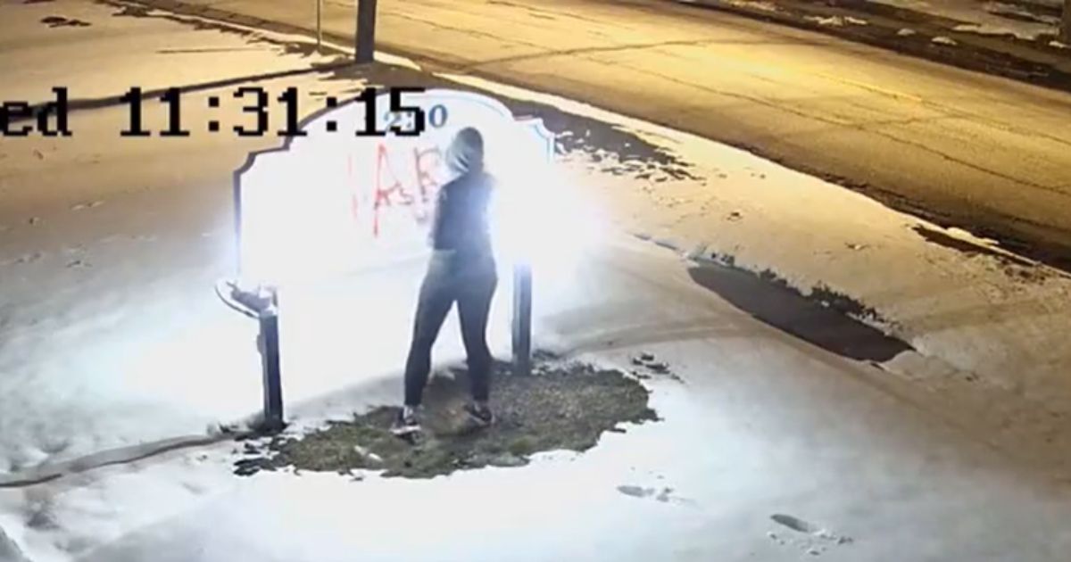 A woman identified as Hannah Kamke, 39, paints graffiti on the sign of a pro-life pregnancy center in Amherst, New York.