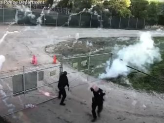 Police officers struggle to secure a gate as they are bombarded with fireworks.