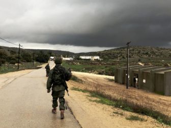 An Israel Defense Force soldier walks by a shooting range on a rainy day.