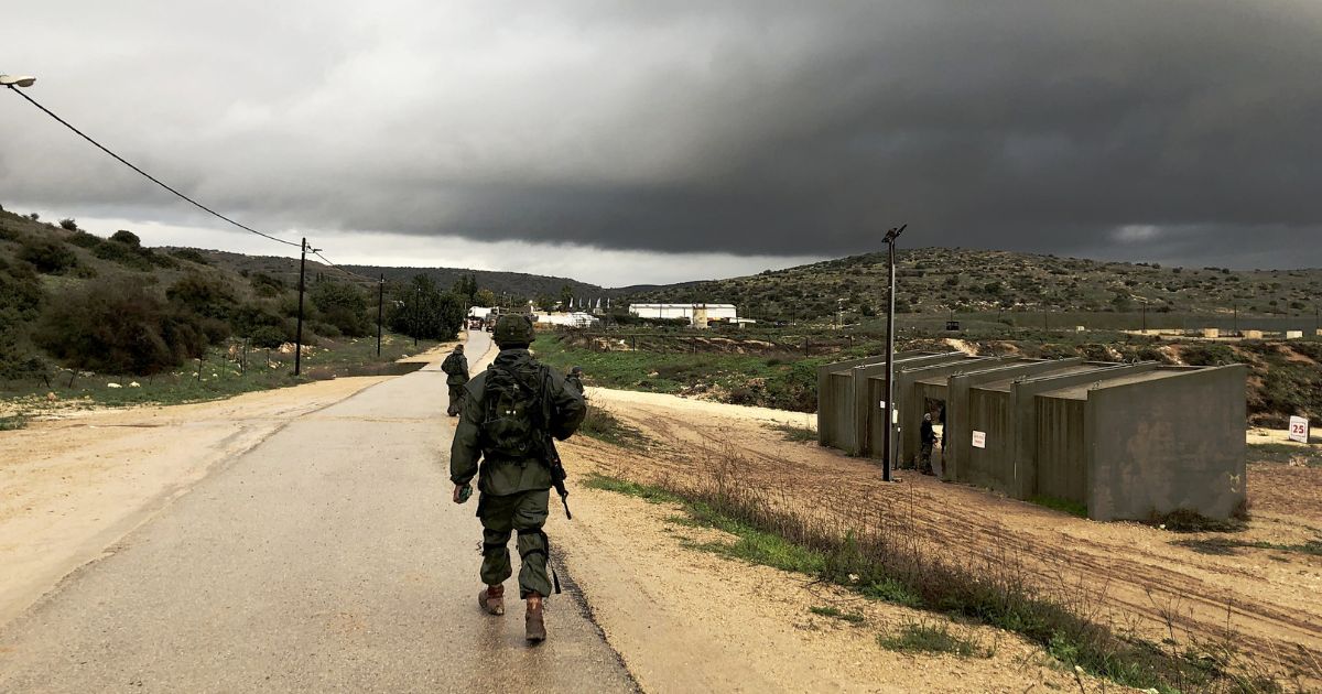 An Israel Defense Force soldier walks by a shooting range on a rainy day.