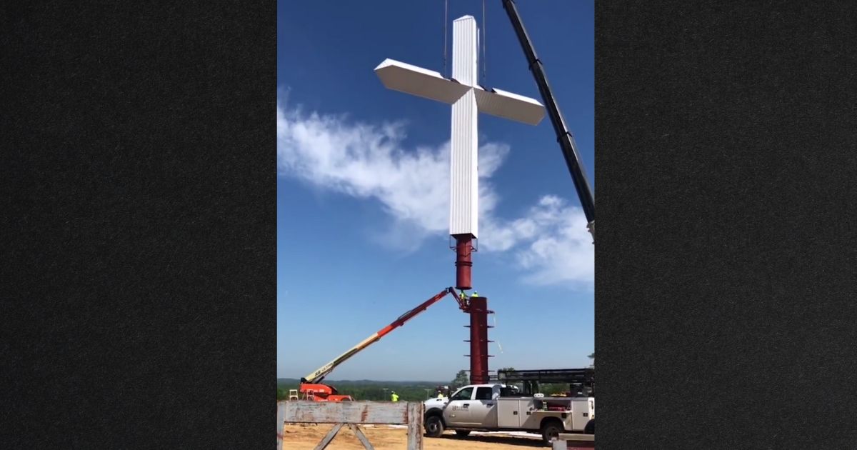 Hundreds stopped to watch a crew raise the cross Thursday in Priceville, Alabama.