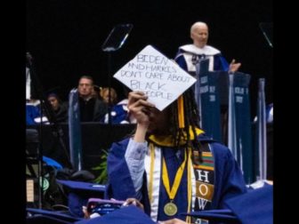 A graduating student at Howard University holds up a sign during President Joe Biden's speech Saturday.