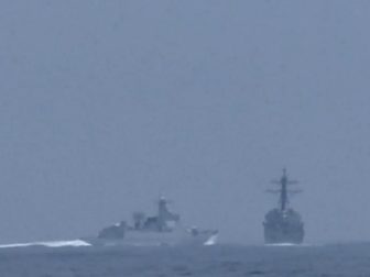 A Chinese naval vessell, left, heads toward overtaking and cutting off an American destroyer in the Taiwan Strait on Saturday.