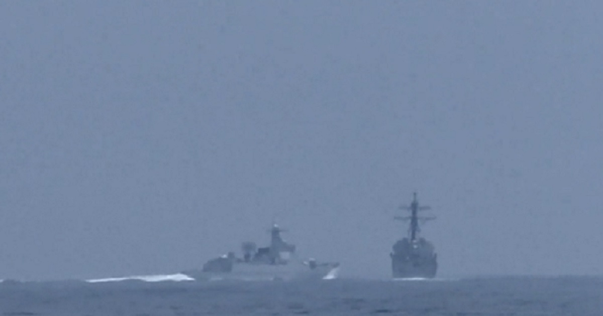 A Chinese naval vessell, left, heads toward overtaking and cutting off an American destroyer in the Taiwan Strait on Saturday.