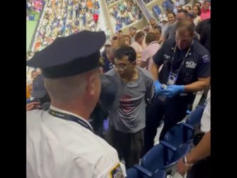 Two men have been charged after they staged a climate protest during a U.S. Open tennis match on Thursday.