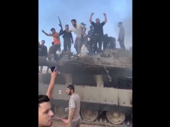 Hamas fighters are seen with a disabled Israeli tank its captured crew on the morning of Oct. 7, 2023.