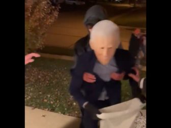 A kid in a Joe Biden costume stumbles up some stairs on Halloween.