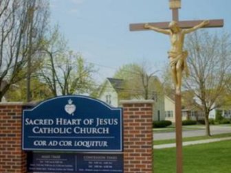 A sign and crucifix outside Sacred Heart of Jesus Parish and school in Grand Rapids, Michigan.