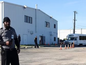 A security guard stands near a San Antonio airport hangar that houses illegal immigrants.