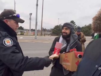 A Toronto police officer delivers coffee to anti-Israel protesters.